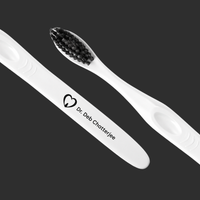 White engraved toothbrushes with soft black bristles and clinic logo