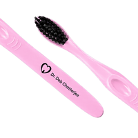 Pink engraved toothbrushes with soft black bristles and clinic logo